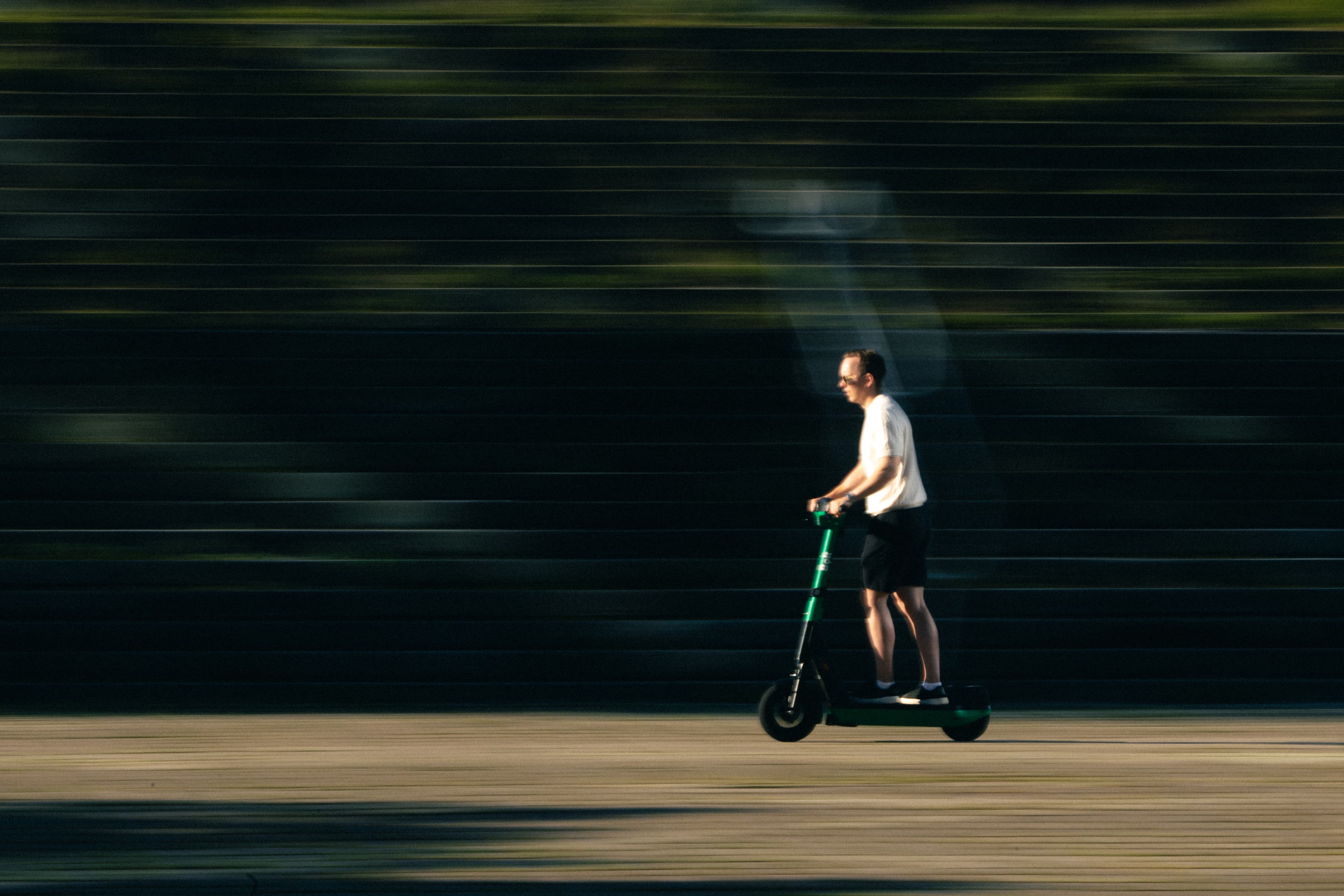 Man riding a Bolt scooter, background blurred by motion