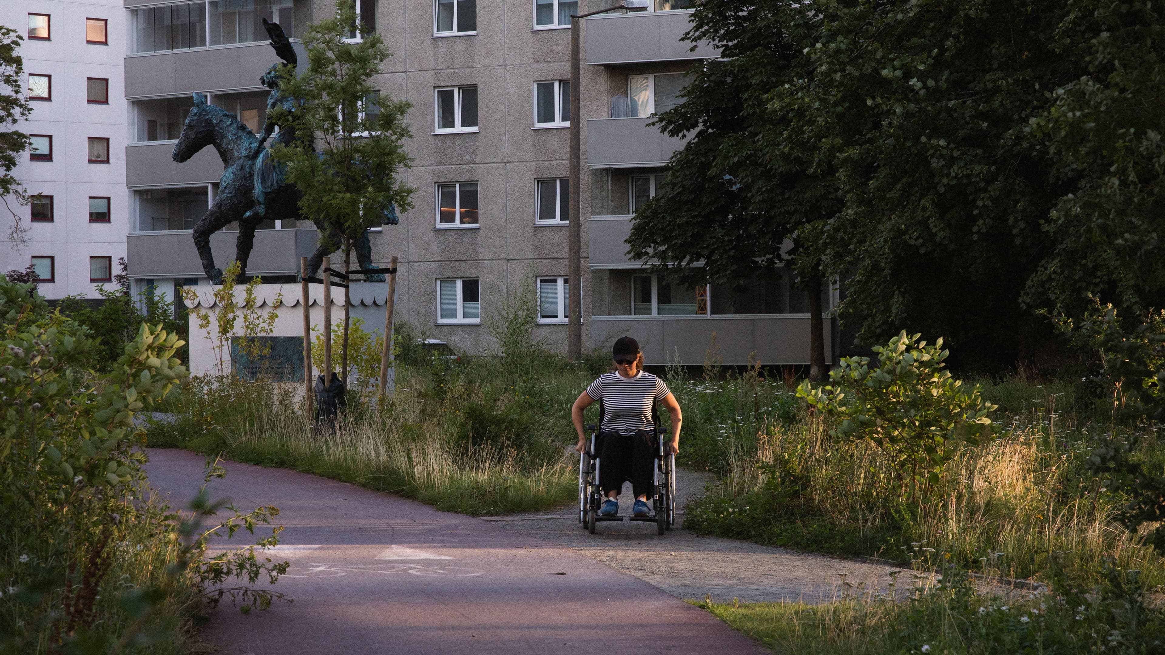 Wheelchair user on a suburban pathway near a park