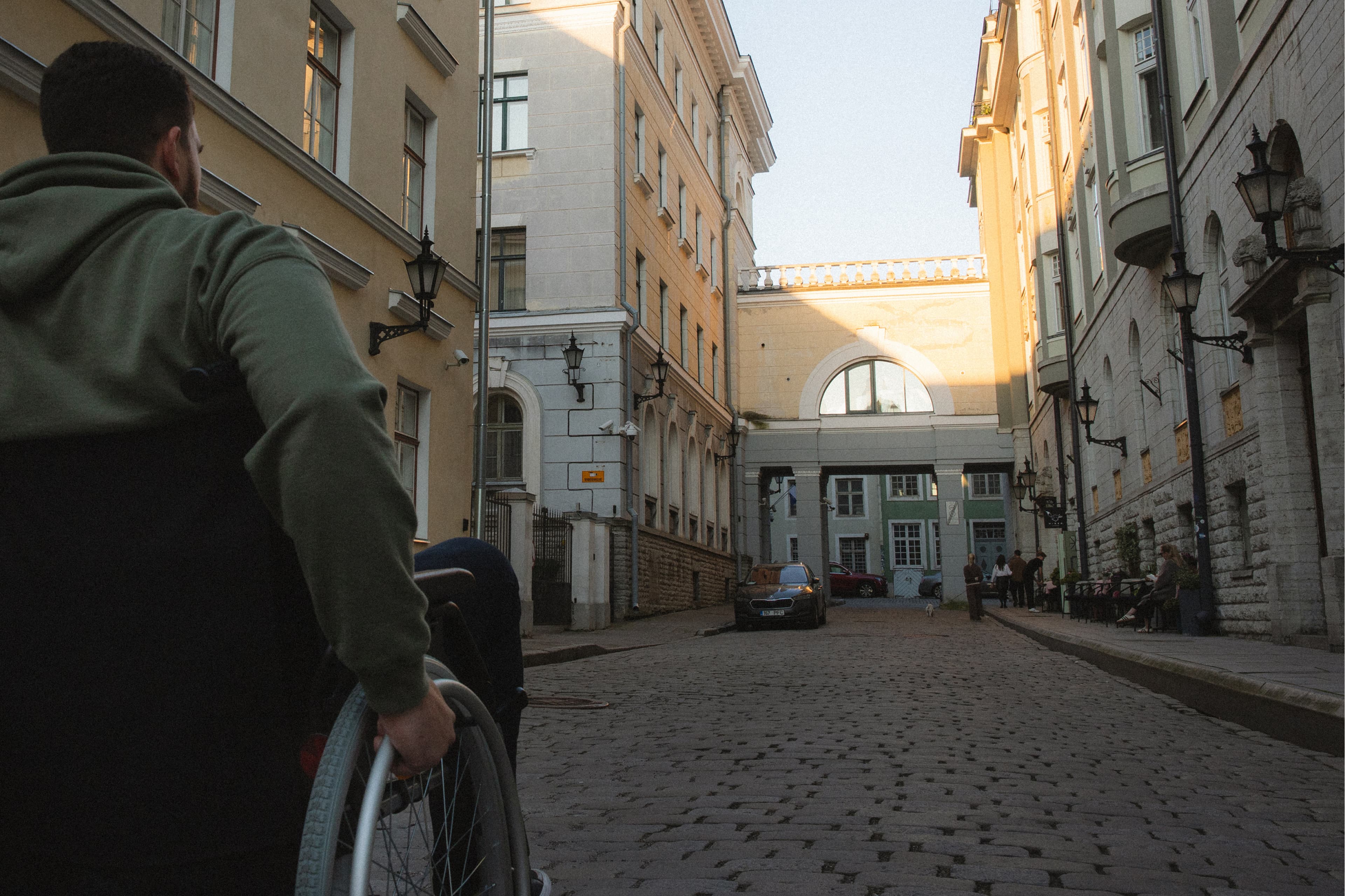 View from behind a wheelchair user moving down a cobblestone street