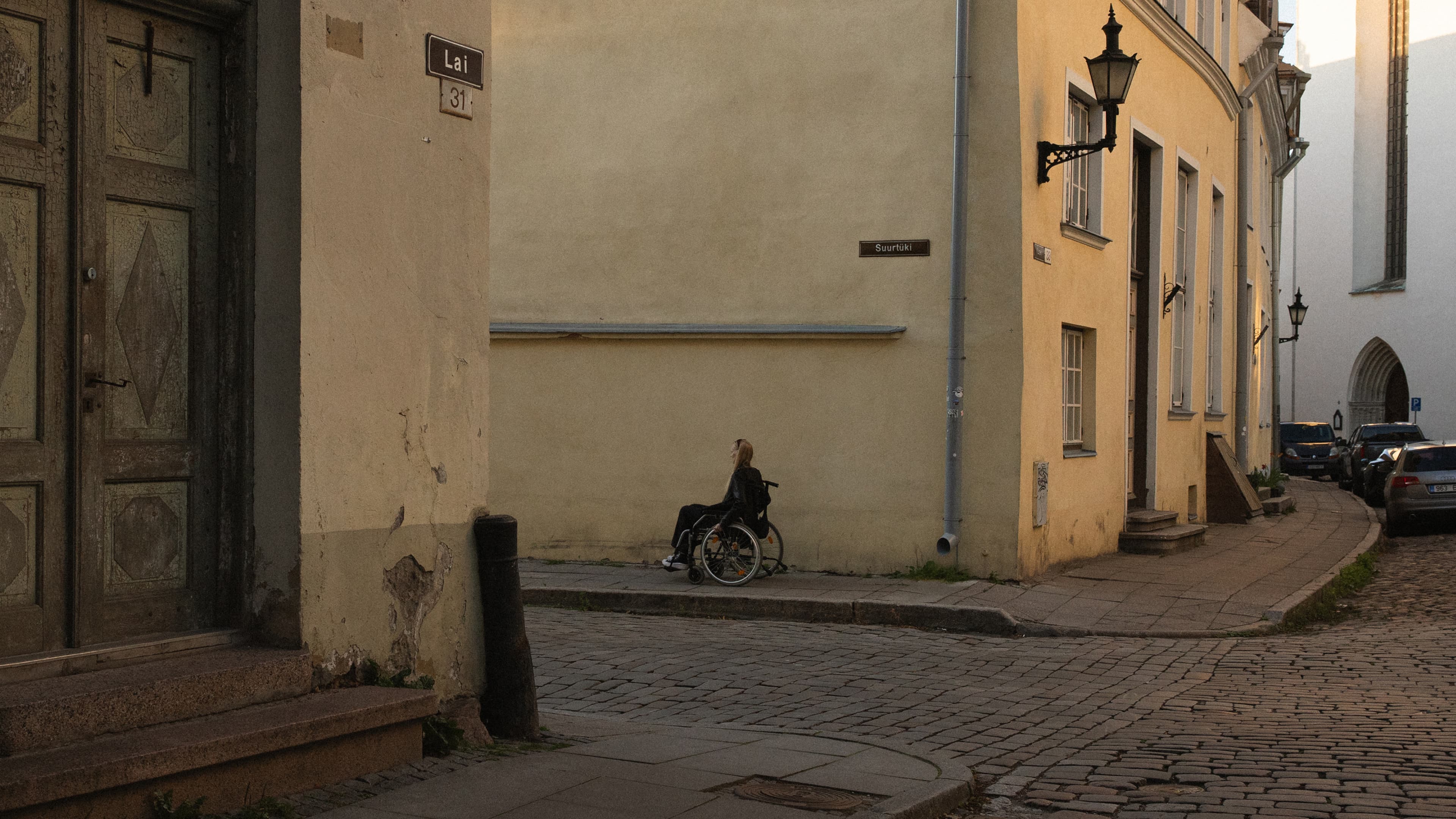 Wheelchair user on a narrow sidewalk in an old-town alley
