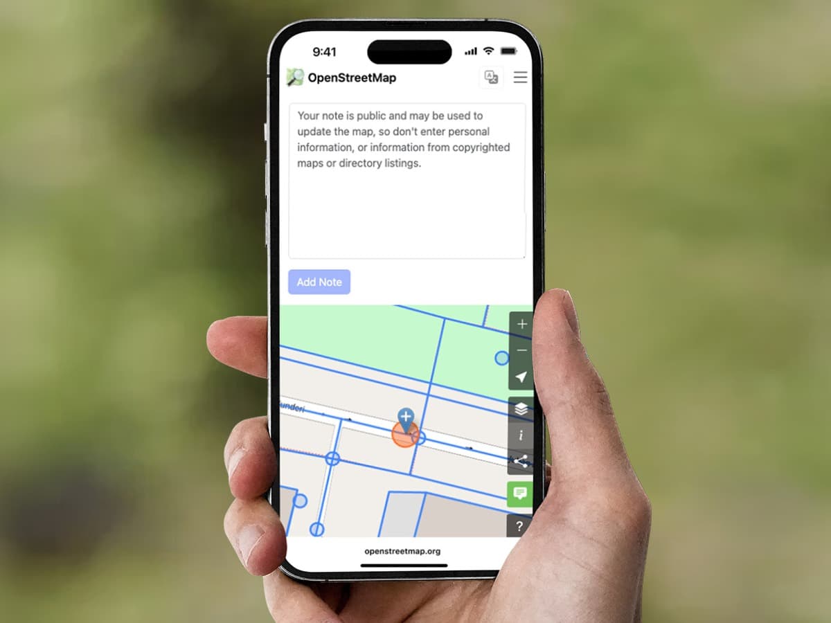 Hand holding a phone showing an OpenStreetMap note screen