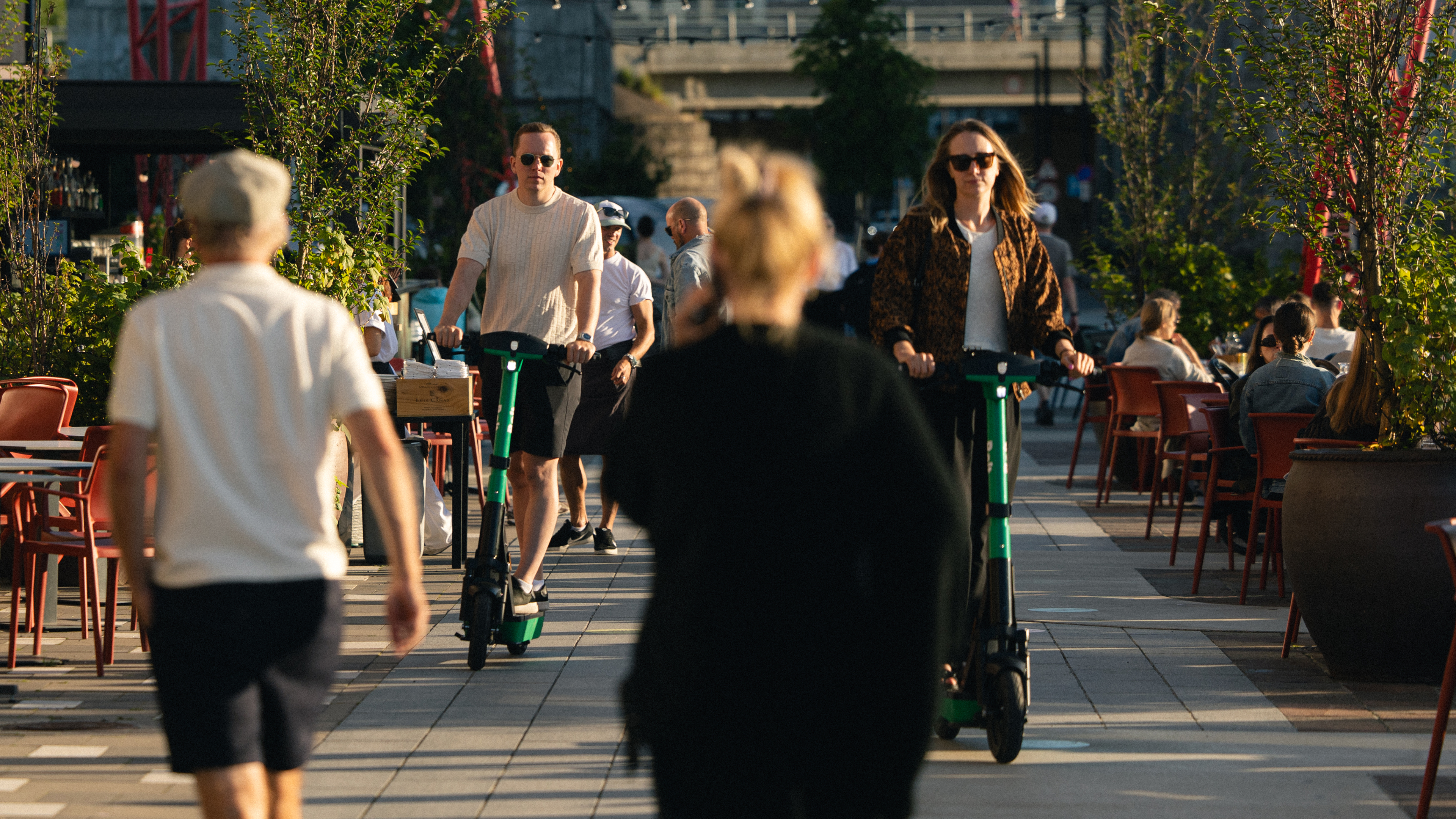 People walking and riding Bolt scooters on a promenade