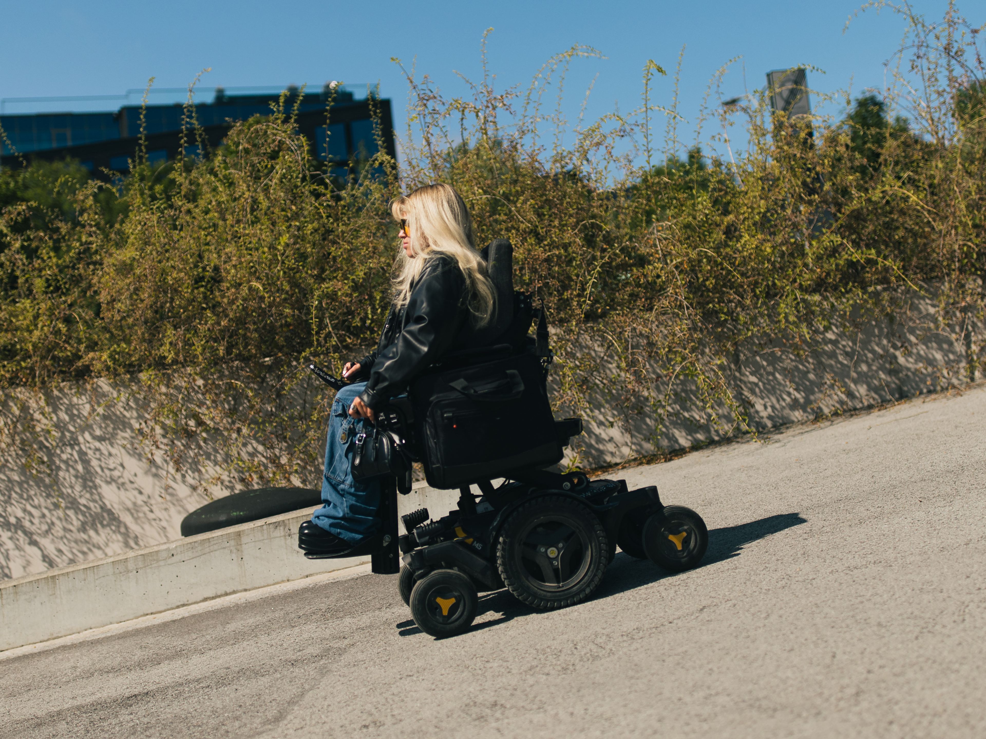 Hendra Raud in her powered wheelchair ascending an asphalt slope